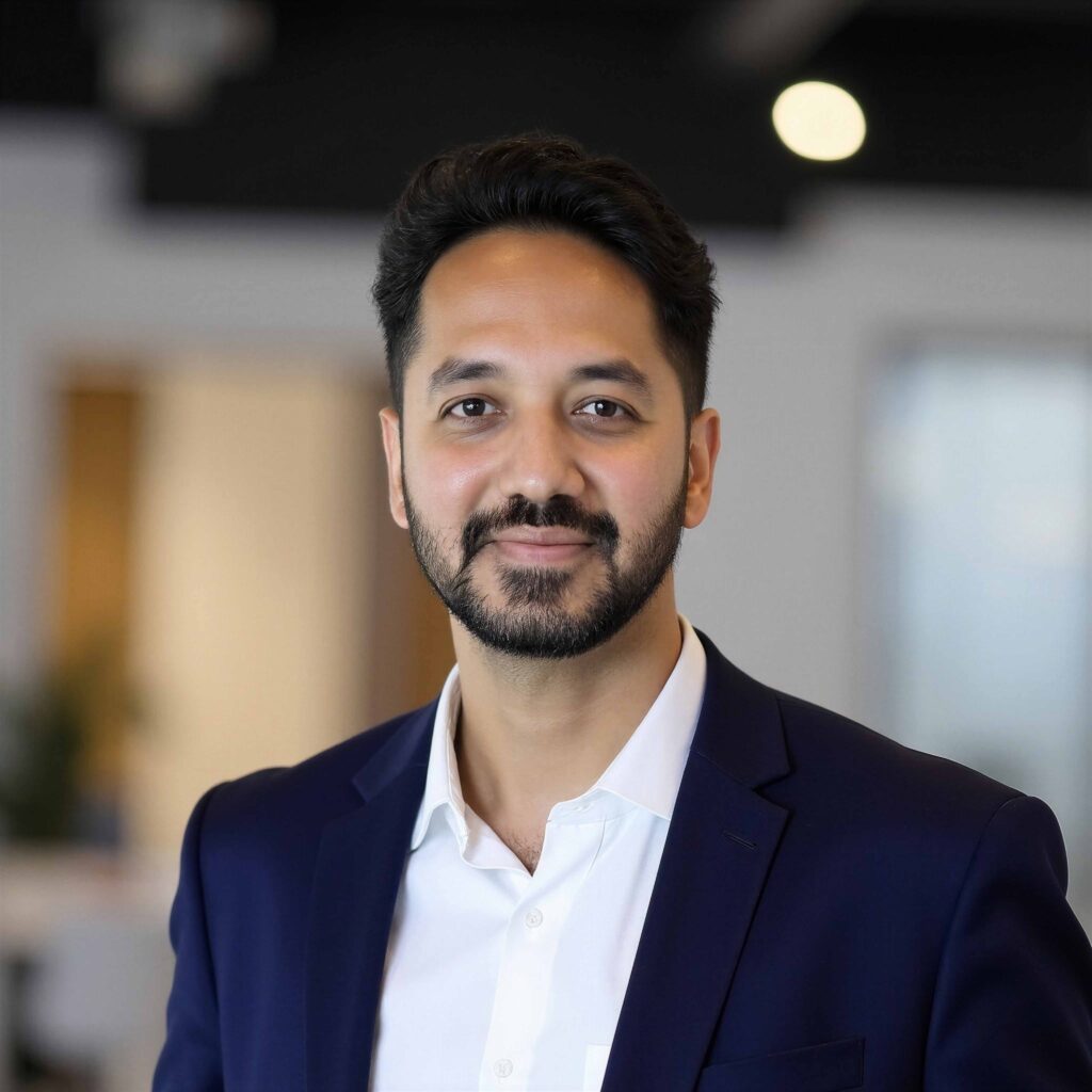 d557815e0c29ac9e – Prolimehost Close-up portrait of a man with dark hair and a beard, wearing a navy blazer and white shirt indoors, smiling slightly